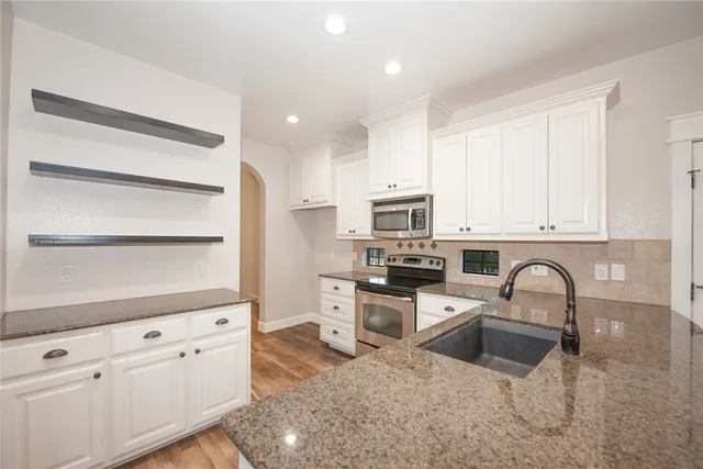 a kitchen with stainless steel appliances granite countertop a stove a sink and a refrigerator