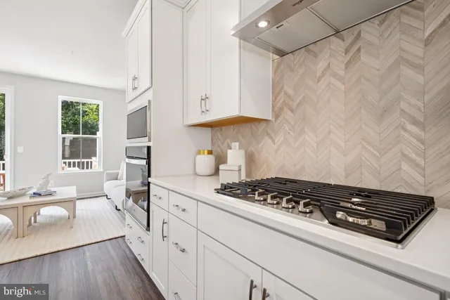 a kitchen with stainless steel appliances granite countertop a stove a sink dishwasher and cabinets with wooden floor