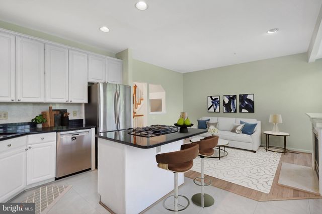 a kitchen with stainless steel appliances granite countertop a refrigerator sink and white cabinets