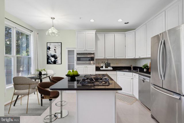 a kitchen with stainless steel appliances a refrigerator a stove a sink a dining table and chairs