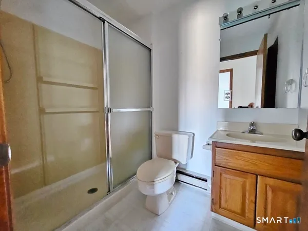 a bathroom with a granite countertop sink toilet a mirror and shower