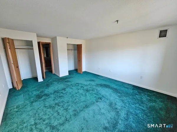 a view of an empty room with closet and stairs