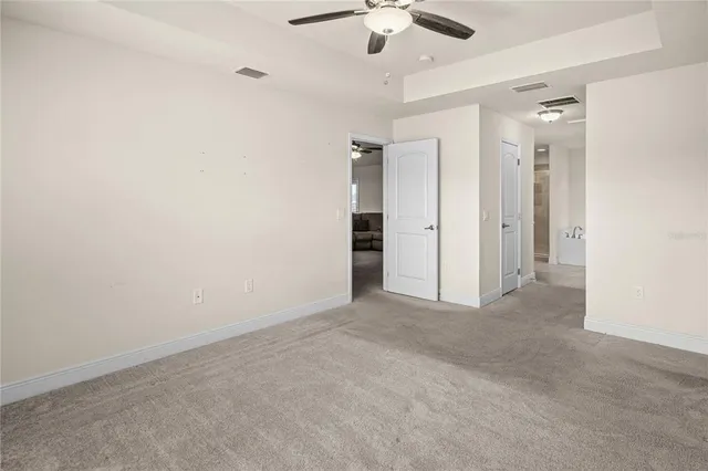 an empty room with chandelier fan and closet area