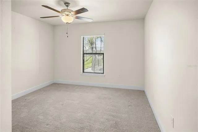 an empty room with a window and a fan
