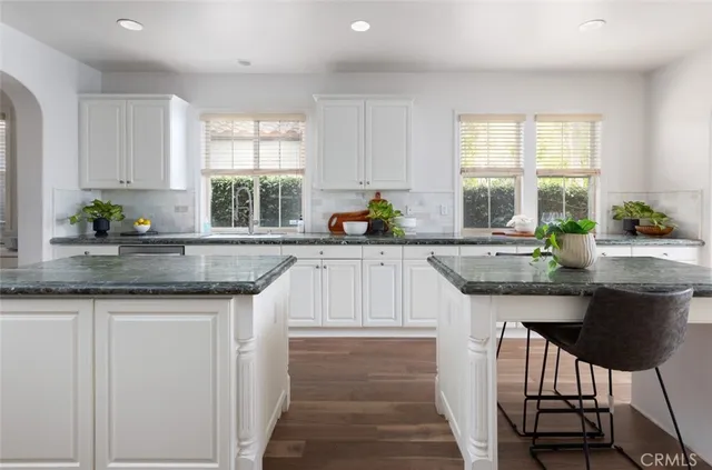 a kitchen with granite countertop a sink chairs and window
