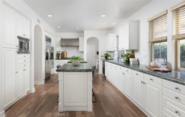 a large kitchen with granite countertop a large counter top appliances and cabinets