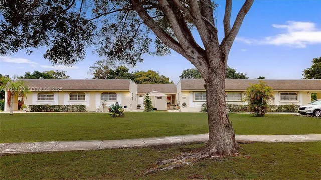 a front view of a house with a garden and trees
