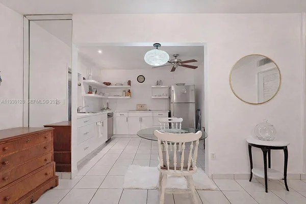 a room with stainless steel appliances kitchen island granite countertop a table chairs and a refrigerator