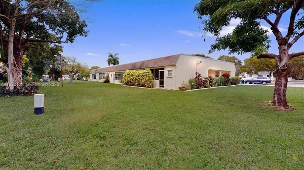 a view of a house with a big yard and large trees