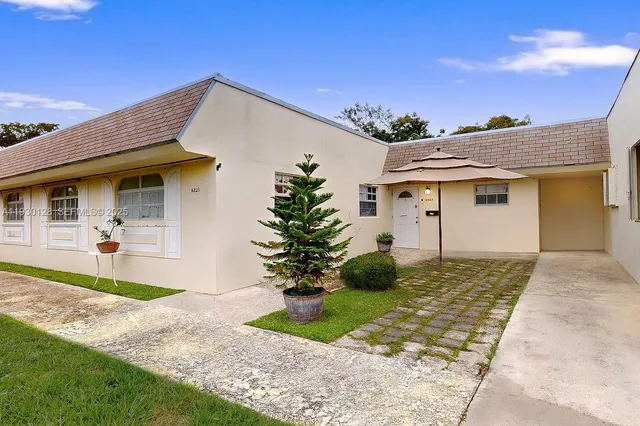 a view of a white house with a small yard and a large tree