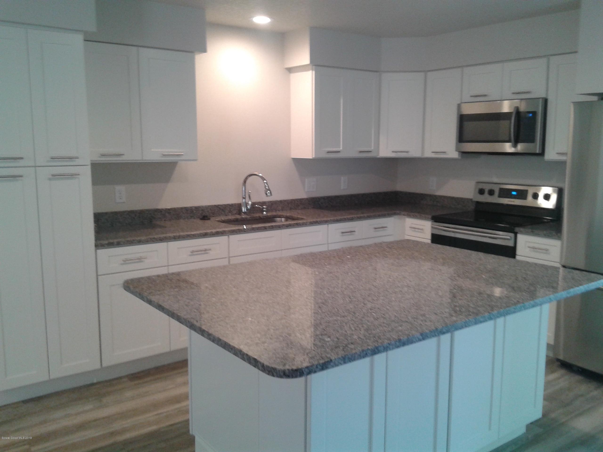 1851 Keewin Avenue, Unit 2 Palm Bay, FL 32905 - Photo 3 of 15 a kitchen with stainless steel appliances granite countertop a sink a microwave and wooden cabinets