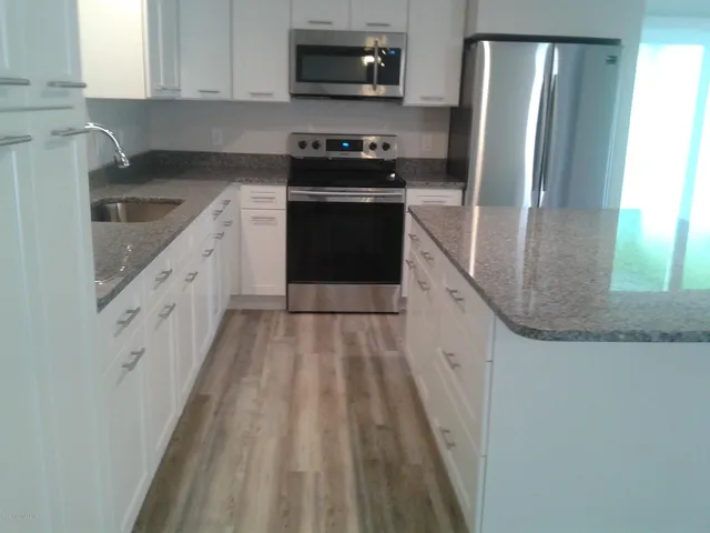 a kitchen with granite countertop a refrigerator stove and sink
