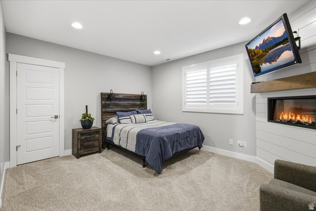 21 Pier Place Tooele, UT 84074 - Photo 75 of 112 Carpeted bedroom featuring a built-in fireplace with a wood mantle, white shiplap-style wall, and a window with plantation shutters