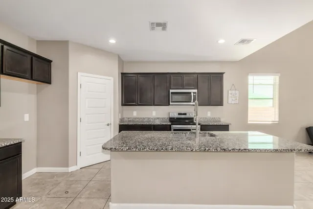 a kitchen with granite countertop a sink a stove top oven a counter space and cabinets