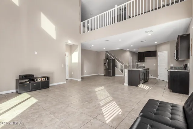 a living room with stainless steel appliances furniture a rug and a kitchen view
