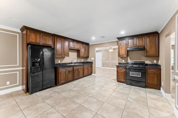 a kitchen with granite countertop a refrigerator stove top oven and sink