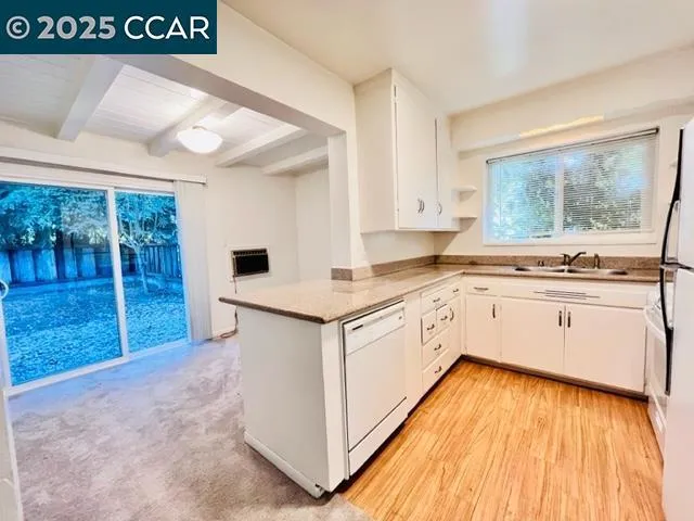 a kitchen with granite countertop a stove a sink and white cabinets with wooden floor