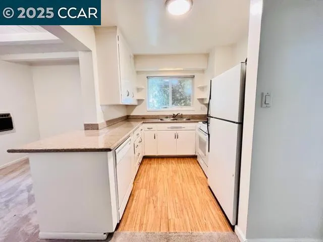 a kitchen with a sink a refrigerator and wooden floor
