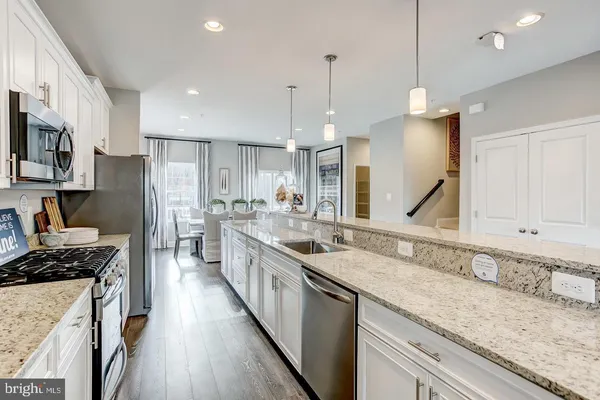 a kitchen with stainless steel appliances granite countertop a sink a stove a refrigerator and a wooden floor