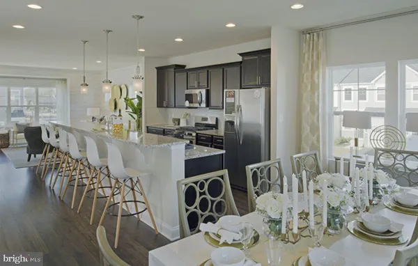 a kitchen with stainless steel appliances kitchen island granite countertop a refrigerator a stove a microwave oven a dining table and chairs with wooden floor