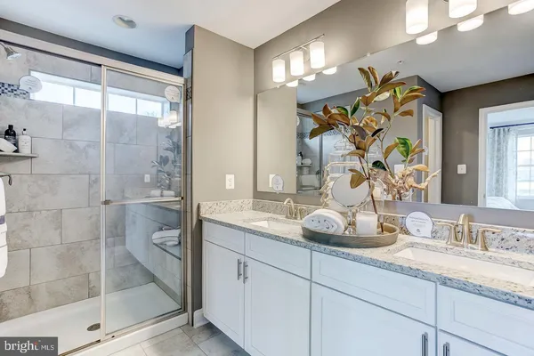 a bathroom with a granite countertop sink a mirror and shower