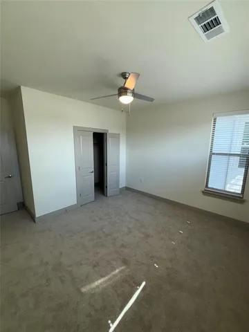 an empty room with closet and a chandelier fan
