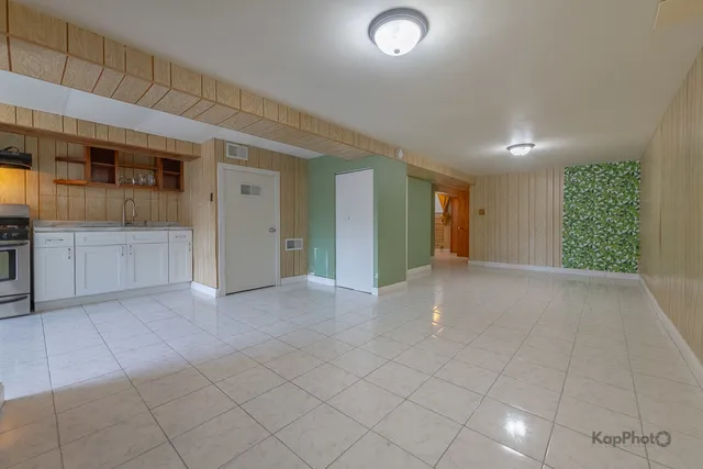 an empty room & kitchen space with a sink window