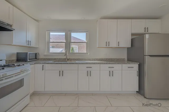 a kitchen with granite countertop white cabinets and white appliances