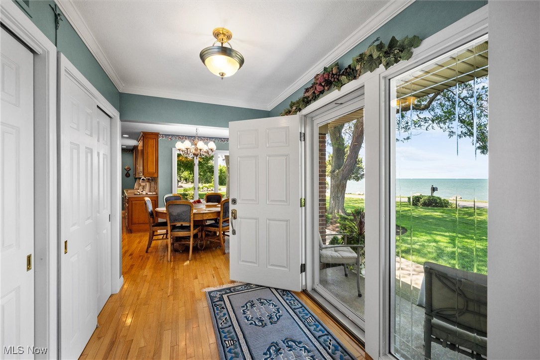 4520 East Cliff Road Port Clinton, OH 43452 - Photo 8 of 50 Entryway with a water view, hardwood / wood-style floors, ornamental molding, and a chandelier