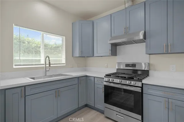 a kitchen with granite countertop white cabinets appliances a sink and a window