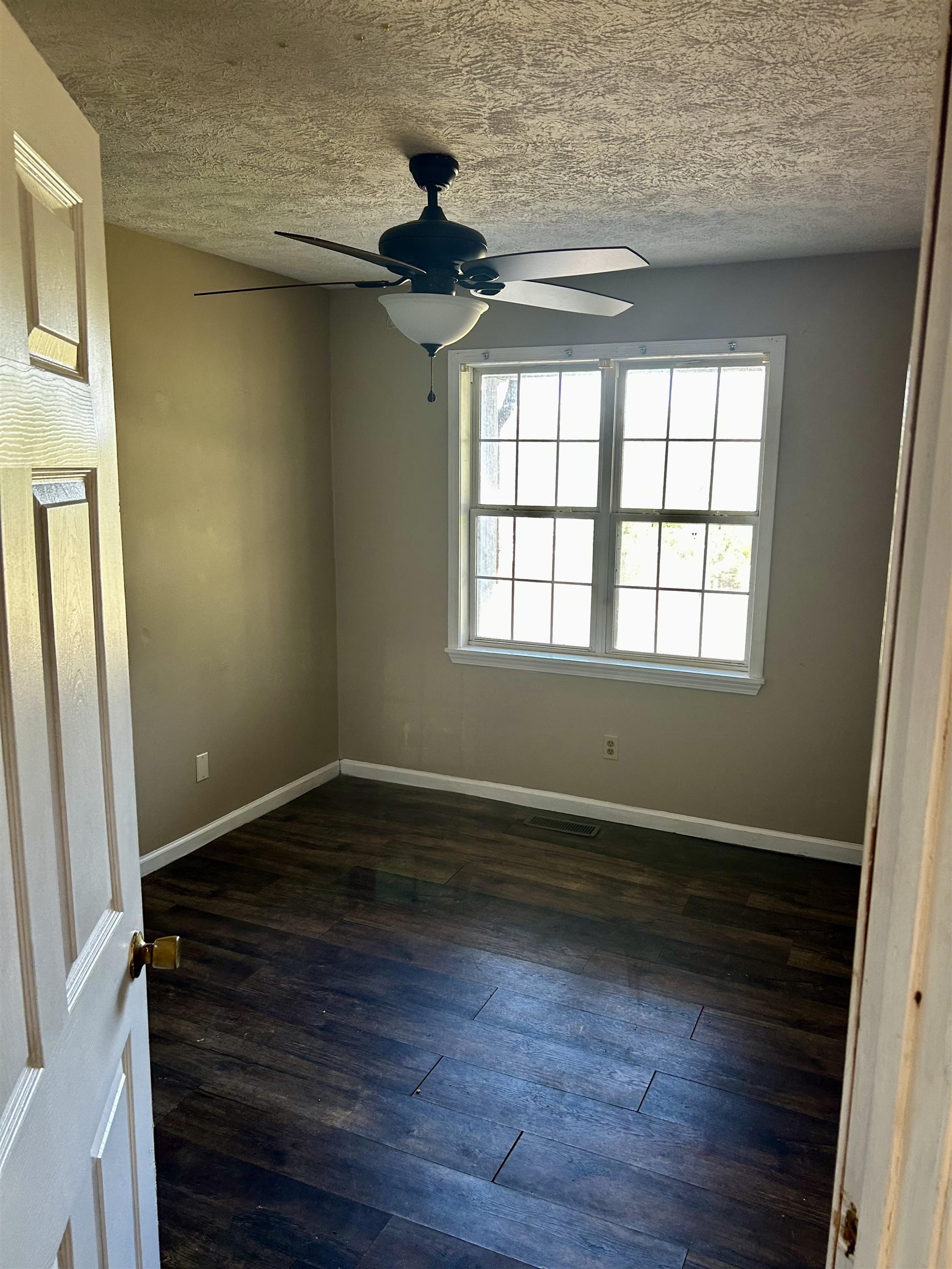 437 Wayne Elam Road Ramer, TN 38367 - Photo 10 of 16 Unfurnished room featuring dark hardwood / wood-style floors, ceiling fan, and a textured ceiling