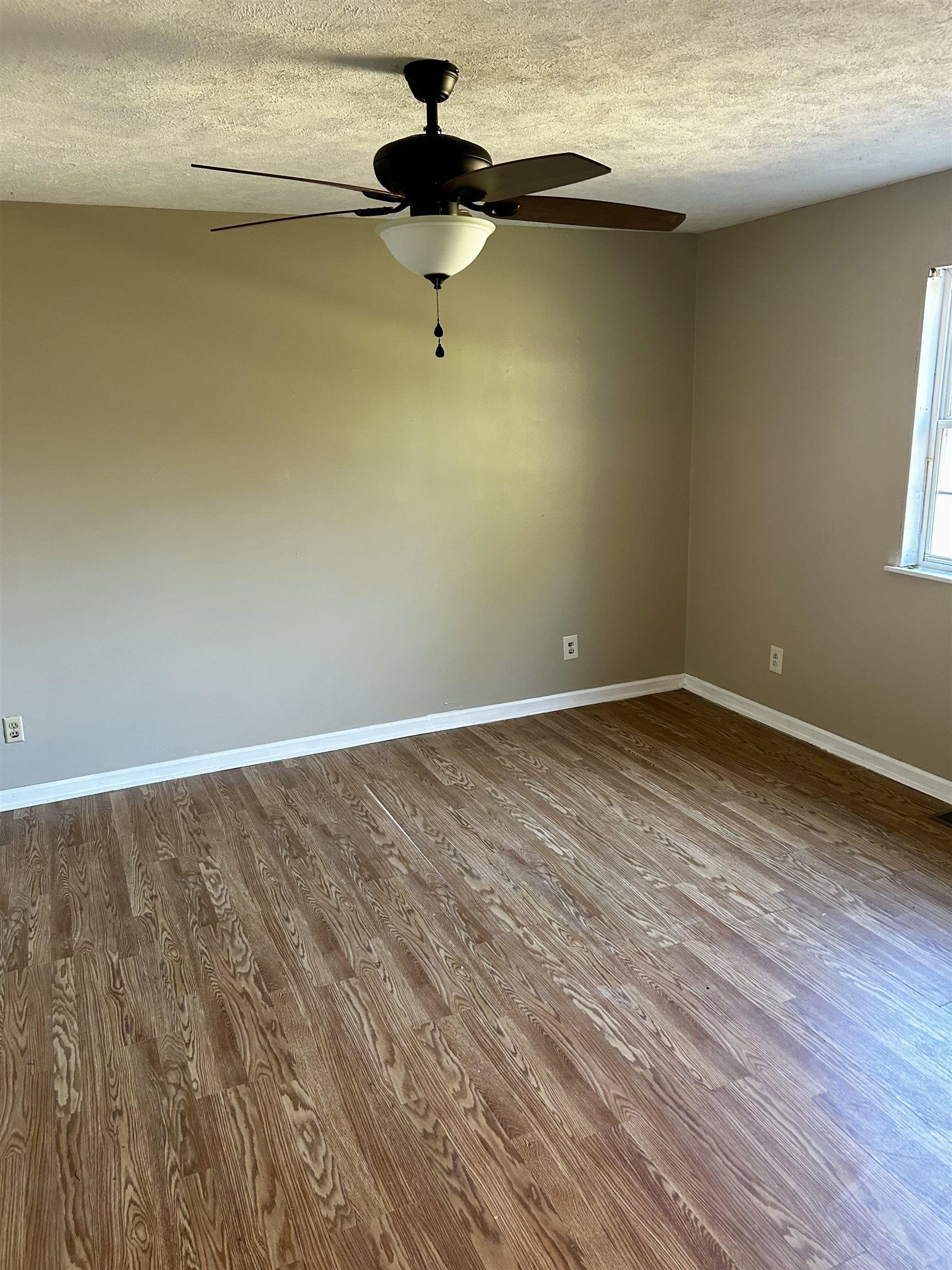 437 Wayne Elam Road Ramer, TN 38367 - Photo 13 of 16 Unfurnished room with ceiling fan, wood-type flooring, and a textured ceiling
