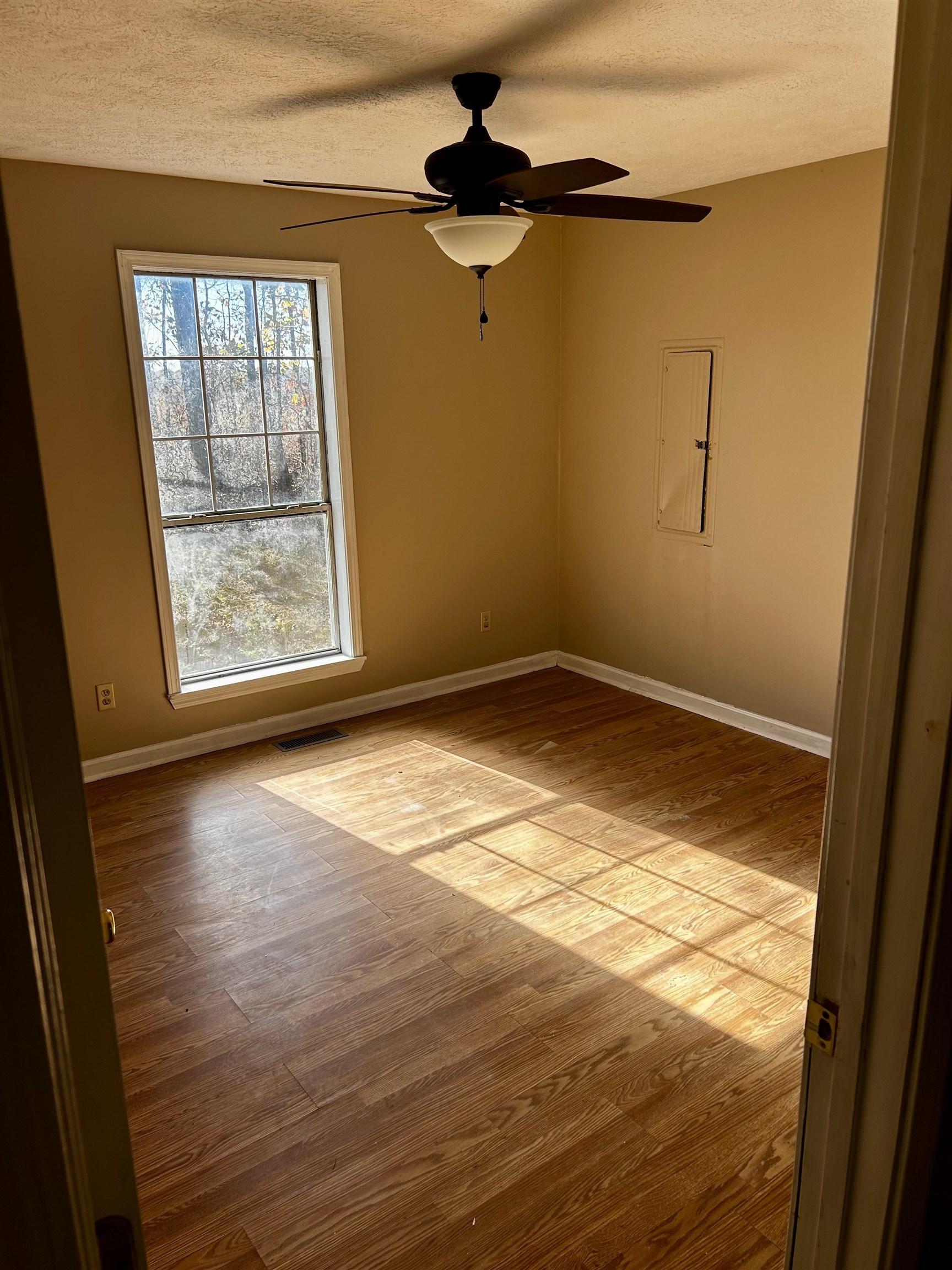 437 Wayne Elam Road Ramer, TN 38367 - Photo 9 of 16 Unfurnished room with a textured ceiling, light wood-type flooring, and ceiling fan