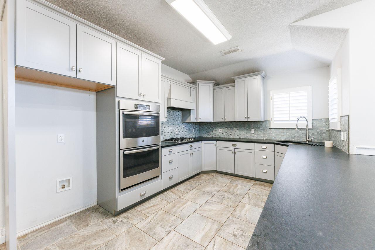4503 108th Street Lubbock, TX 79424 - Photo 13 of 53 a kitchen with stainless steel appliances granite countertop a stove a sink and a refrigerator