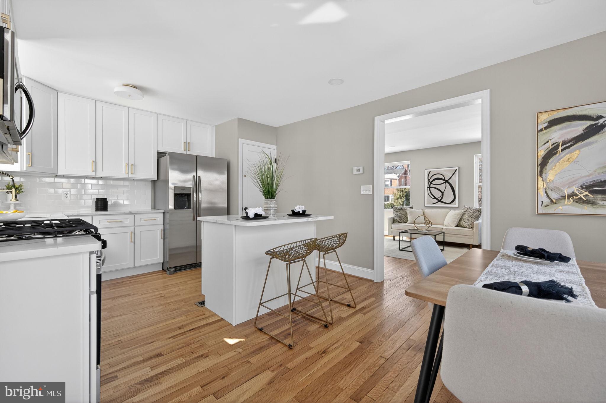 914 Dennis Avenue Silver Spring, MD 20901 - Photo 14 of 37 a kitchen with a refrigerator a stove top oven a dining table and chairs with wooden floor