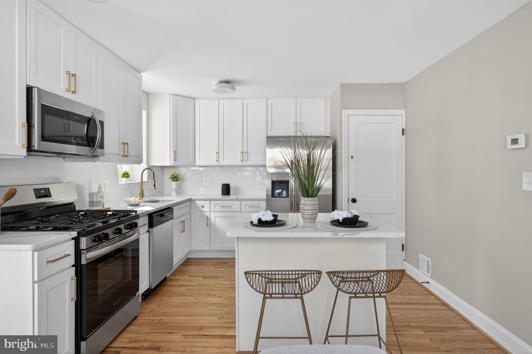 914 Dennis Avenue Silver Spring, MD 20901 - Photo 15 of 37 a kitchen with stainless steel appliances granite countertop a stove top oven a sink dishwasher and a refrigerator with wooden floor