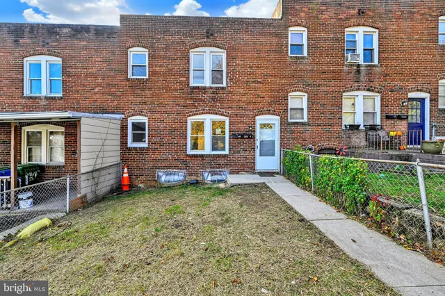a view of brick house with a yard and table and chairs and potted plants