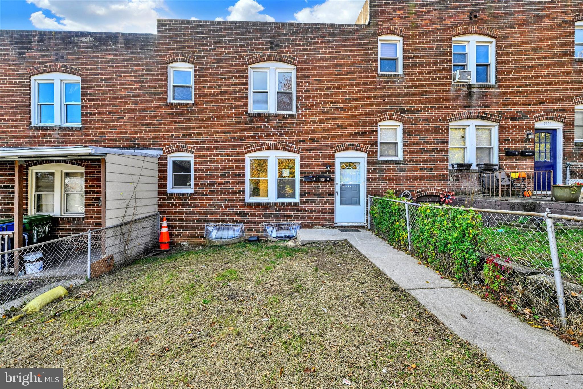 a view of brick house with a yard and table and chairs and potted plants