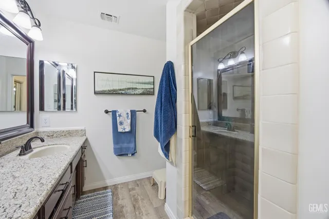a bathroom with a granite countertop sink a mirror and shower