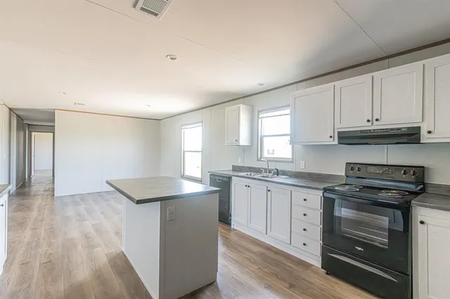 a kitchen with granite countertop a sink stove and cabinets