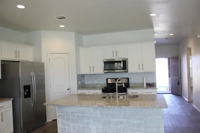 a kitchen with stainless steel appliances granite countertop a refrigerator a stove a microwave and a sink