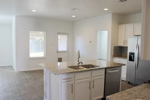a kitchen with kitchen island granite countertop a sink and refrigerator