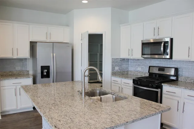a kitchen with kitchen island granite countertop stainless steel appliances a refrigerator and a sink