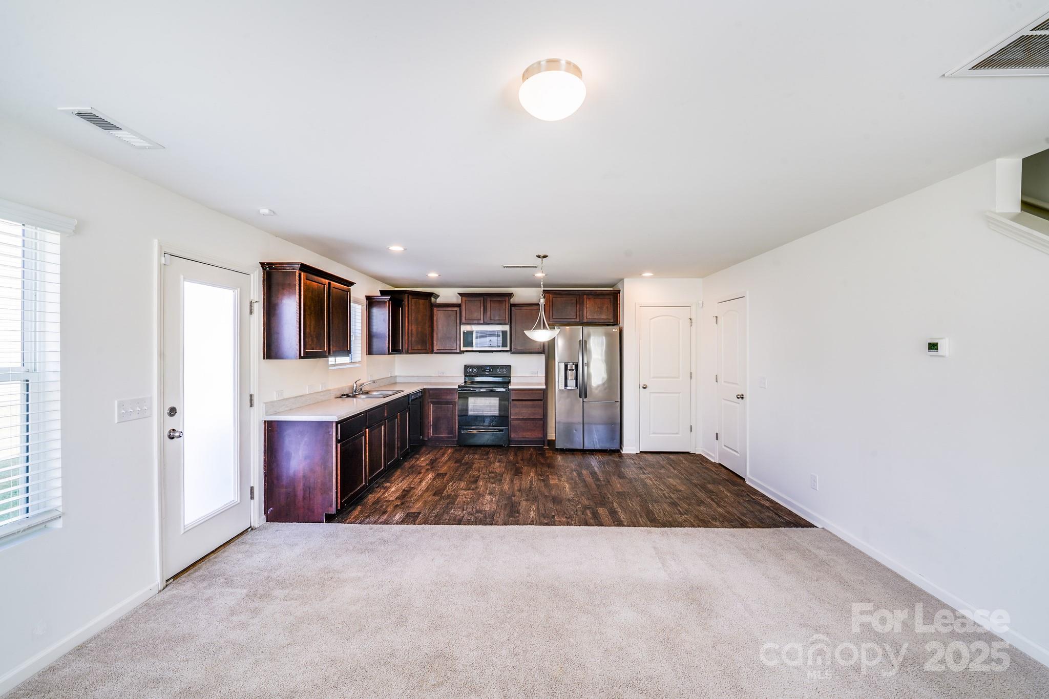 12915 Hill Pine Road Midland, NC 28107 - Photo 14 of 31 a large white kitchen with a stove top oven a sink dishwasher and a refrigerator with wooden floor
