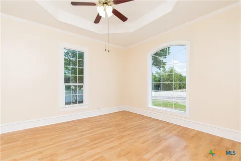 an empty room with wooden floor fan and windows