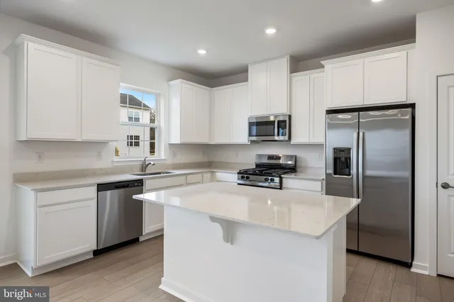 a kitchen with a sink a center island stainless steel appliances cabinets and a window