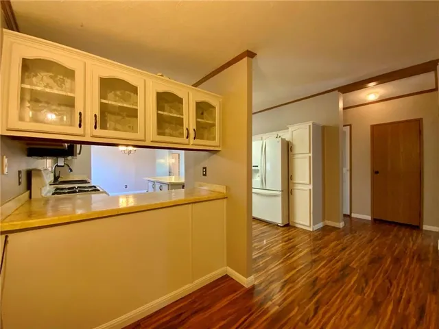 a kitchen with stainless steel appliances granite countertop a refrigerator a stove and a wooden floors