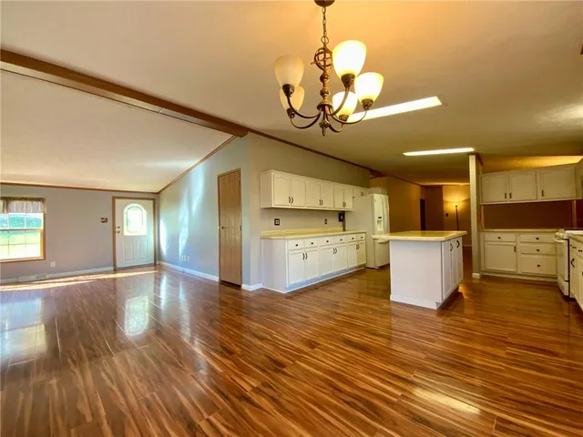 a view of a room with wooden floor and kitchen view