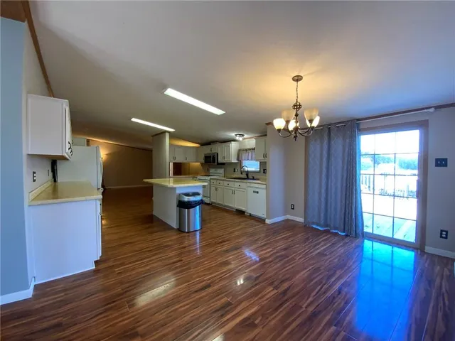 a kitchen with stainless steel appliances granite countertop a refrigerator a sink dishwasher a stove and a dining table with wooden floor