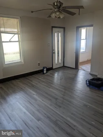 an empty room with wooden floor closet and windows